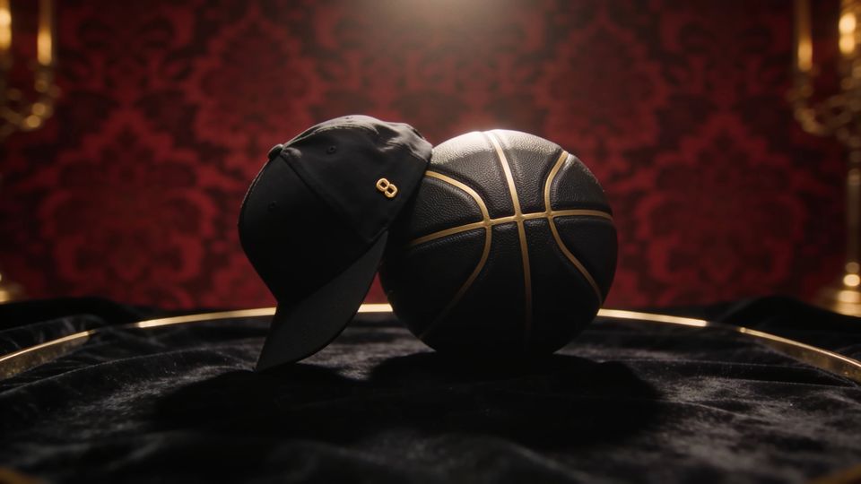A black basketball with gold seams and a black cap with a gold number
